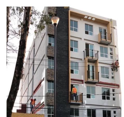 Fachada en proceso de acabado con personal trabajando en balcones