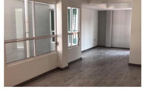 Área social con ventanales y piso de madera laminada